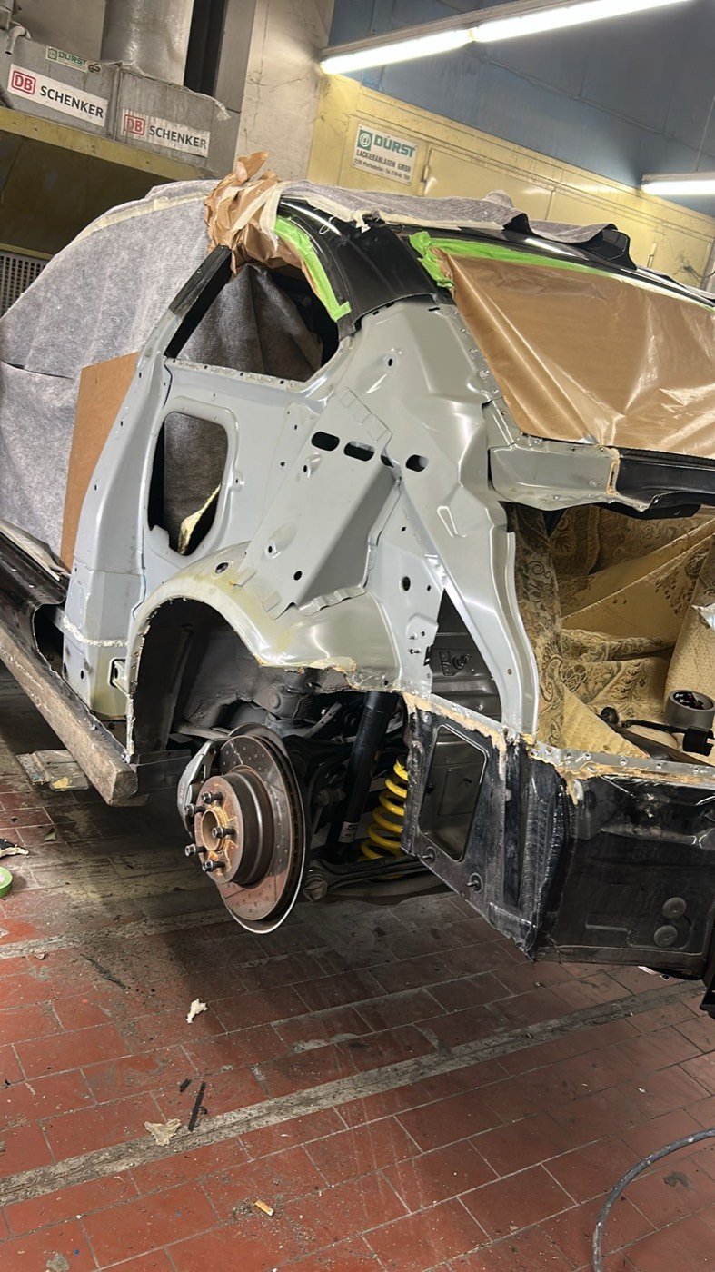Komplett zerlegte Karosserie des BMW 1er auf Böcken in der Garage, Schweißausrüstung im Vordergrund